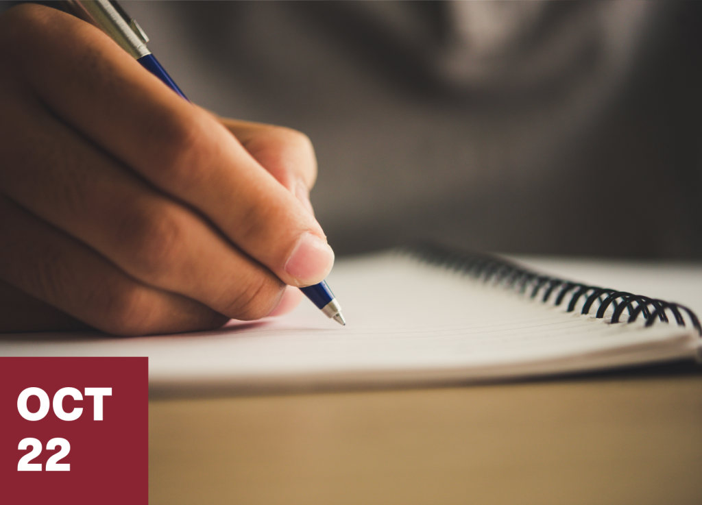 A hand holds a pen and writes in a spiral notebook, perhaps drafting an essay for an mfa-in-creative-writing program. In the bottom left corner, a red box displays OCT 22 in bold white text.