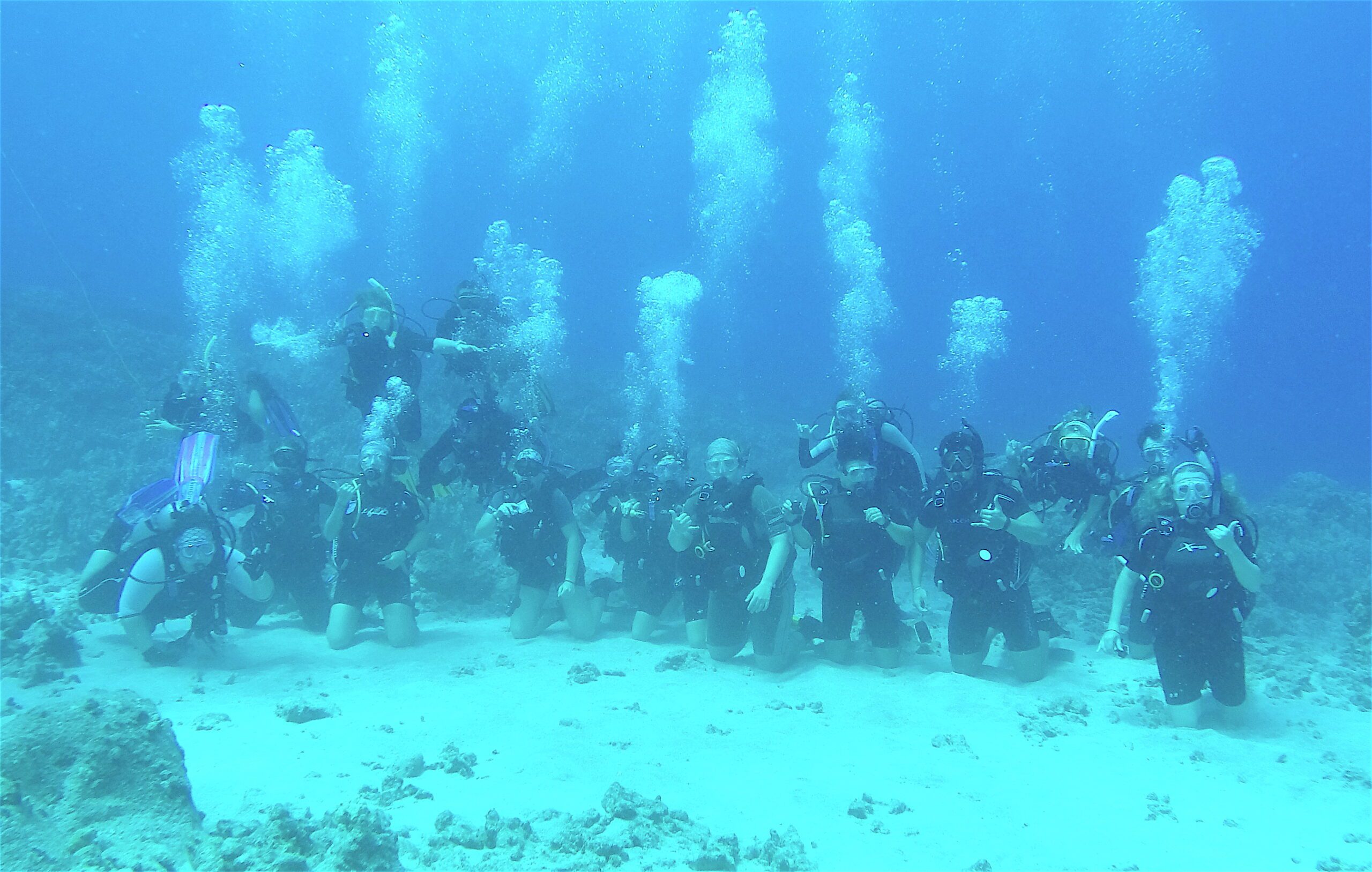 Alma College Students posing for a underwater photo while scuba diving in Hawaii