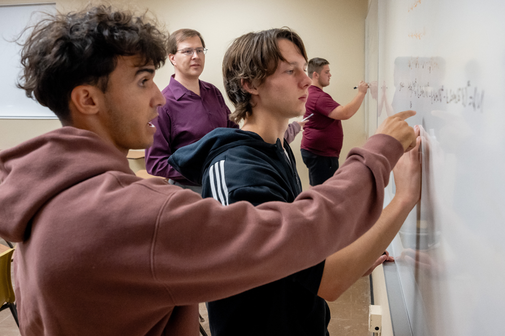 Students working on a problem with a whiteboard while attending a class at Alma College