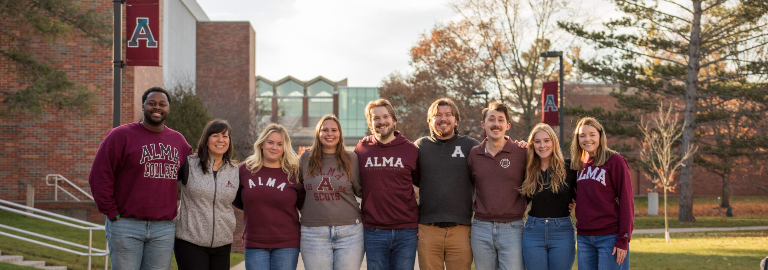 Alma College Admissions Counselors posing for a photo on campus on a fall day.