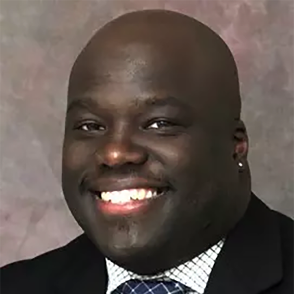 Professional headshot of Phil Miller smiling at the camera in front of a gray background. 