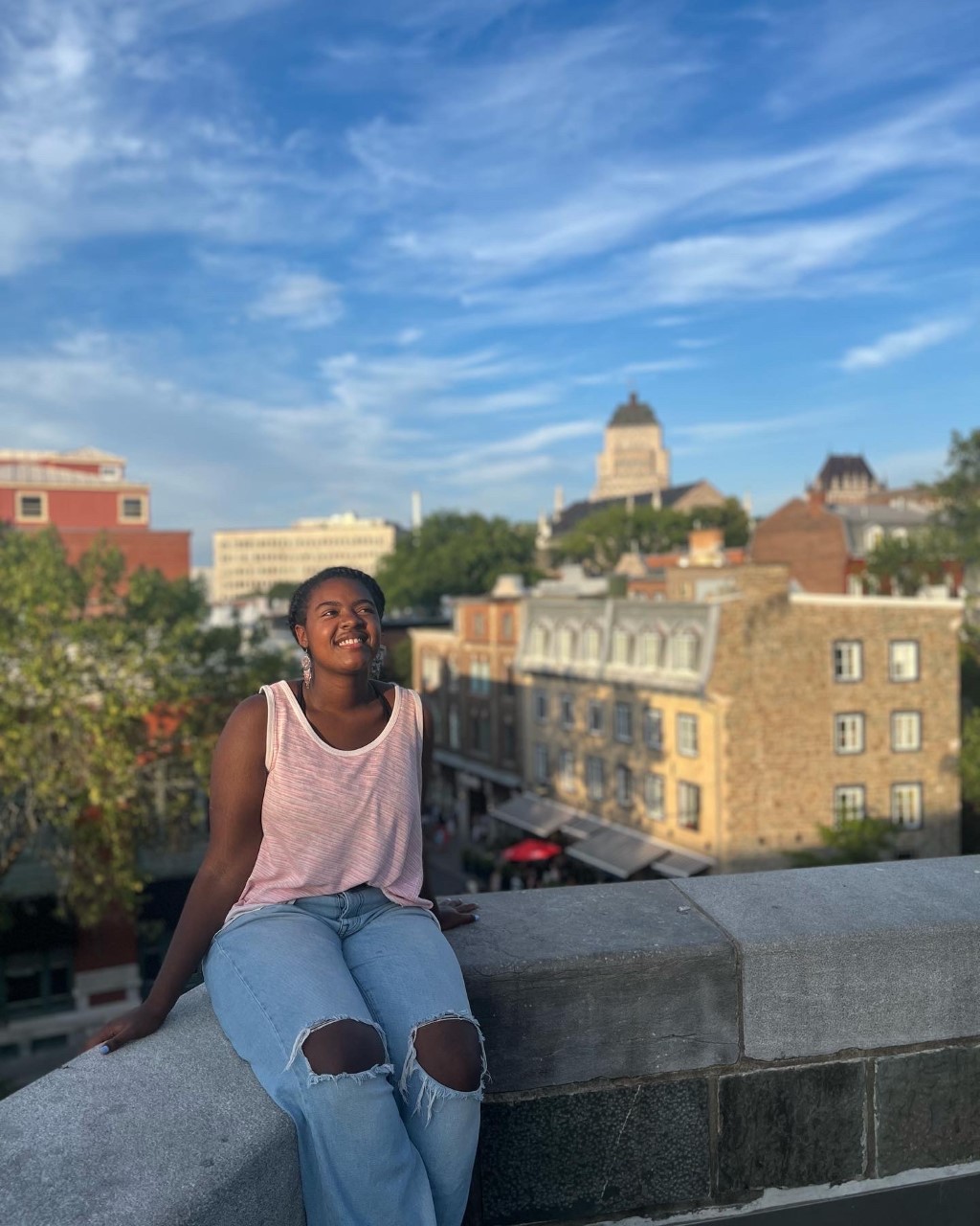 An Alma College Student sits on the balcony of a city abroad while traveling for her Spring Term.