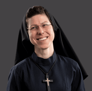 A woman in religious clothing is pictured smiling away from the camera.