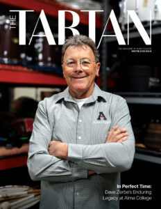 A magazine cover with a middle-aged man as the "main art," wearing a collared shirt and standing before a collection of marching band equipment.