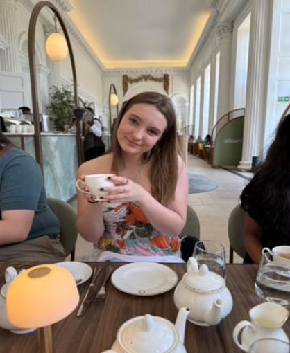 Alma College student sits in a coffee shop with a mug in her hand.