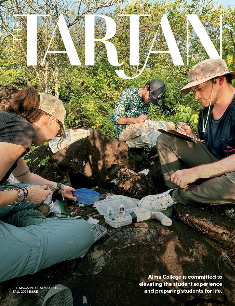 Three students conduct field research outdoors for The Tartan, taking notes and examining specimens on a rocky slope in the Galopagos. 